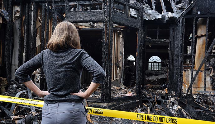 a person standing beside of a burned house